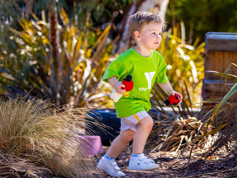 Child running outdoors holding toys